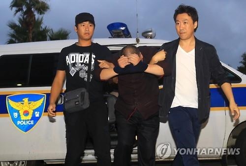 Police officers take a Chinese man, suspected of fatally stabbing a 61-year-old Korean woman who was praying at a local church, to the Jeju Seobu Police Station on the country's resort island of Jeju on Sept. 17, 2016. (Yonhap) 