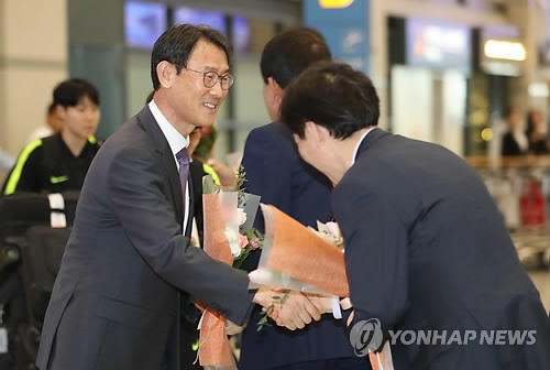 South Korea women's national football team head coach Yoon Duk-yeo (L) is congratulated by Korea Football Association officials at Incheon International Airport in Incheon on April 18, 2018, after his team returned home from Jordan having secured a ticket to the 2019 FIFA Women's World Cup. (Yonhap)