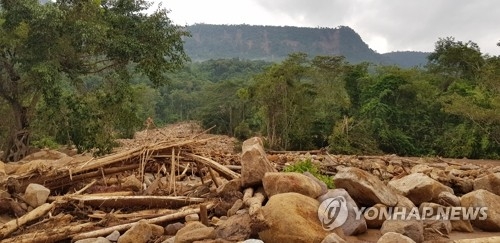 A road to a Laotian village, hit by flash floods caused by a dam failure, is covered with fallen rocks. (Yonhap)