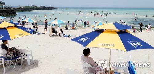 Tourists and Jeju Island residents enjoy themselves at a beach on the southern resort island on July 31, 2020, amid sweltering heat. (Yonhap)