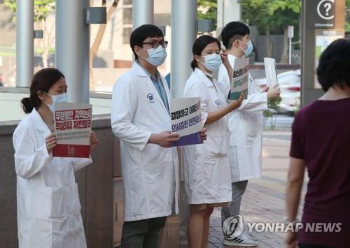 Doctors hold up signs criticizing the government at a Seoul hospital on Aug. 26, 2020, as tens of thousands of doctors went on a full-scale strike nationwide for a three-day run earlier in the day in protest of the government's medical workforce reform. (Yonhap)