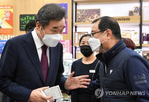 This photo provided by the National Assembly press corps shows Democratic Party Chairman Rep. Lee Nak-yon talking to a business owner in Seoul on Jan. 14, 2021, while inspecting business establishments hit by the new coronavirus pandemic. (PHOTO NOT FOR SALE) (Yonhap)