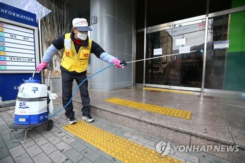 Un employé de la municipalité de Daegu désinfecte l'entrée d'une église à Daegu, à 300 km au sud-est de Séoul, le mercredi 19 février 2020. La 31e patiente du pays est allée dans cette église alors que les autorités pensent que 10 personnes y ont été infectées par le virus.
