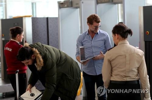 공항에서 기내반입품 검색을 받고 있는 승객들