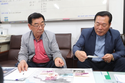 참치잡이 선장으로 근무할 당시 사진을 들고 설명하는 이재옥 씨(왼쪽)와 오성유 씨