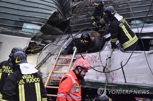25일 이탈리아 밀라노 인근에서 일어난 통근 열차 탈선 사고로 크게 부서진 객차에서 소방대원들이 승객들을 구조하고 있다. [로이터=연합뉴스] 