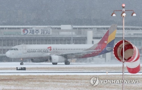 눈 내리는 제주공항에서 이륙 준비하는 아시아나항공 여객기