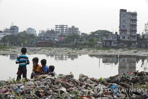 2018년 6월 4일 방글라데시 수도 다카를 지나는 부리강가강변의 쓰레기 더미에 아이들이 앉아 있다. 최근 핀란드 수도 헬싱키에서 발표된 조사 결과에 따르면 방글라데시의 강은 항생제로 심각하게 오염된 것으로 나타났다. [AP=연합뉴스 자료사진]