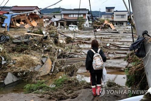 (나가노 AFP=연합뉴스) 제19호 태풍 '하기비스'가 동일본 지역에 큰 피해를 준 가운데 15일 일본 나가노현에서 한 여성이 풍수해를 입은 가옥을 바라보고 있다. 