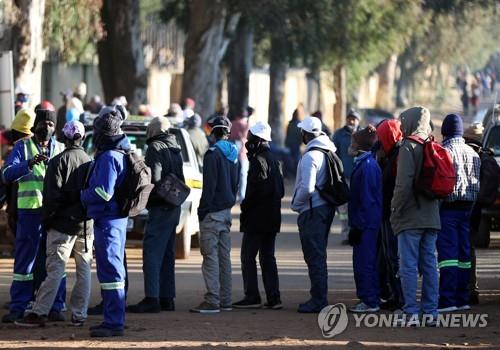 구직자들이 23일 남아공 요하네스버그 남쪽 아이켄호프의 건설부지 밖에 서 있다.