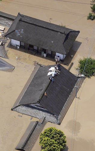 (구마모토 교도=연합뉴스) 4일 폭우에 따른 주변 강의 범람으로 물에 잠긴 구마모토현 히토요시(人吉)시에서 주민들이 주택 지붕 위에 올라가 구조를 기다리고 있다. 