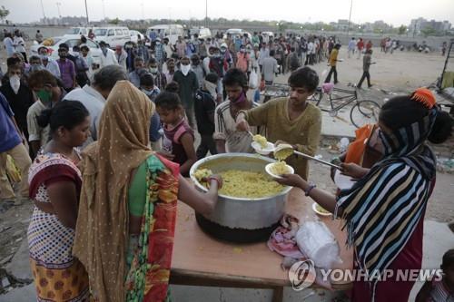 인도 아메다바드의 무료 급식소에 줄을 선 저소득층. 제대로 된 마스크를 착용한 이가 별로 없다. [AP=연합뉴스]