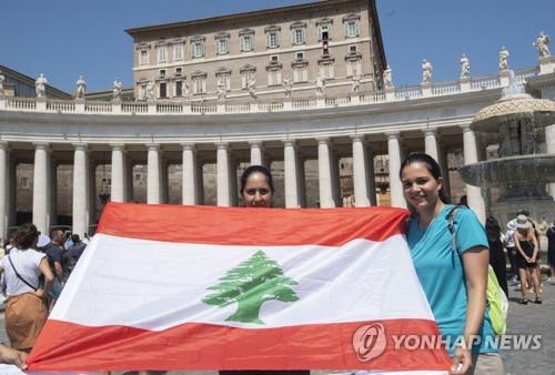 9일 열린 주일 삼종기도회 참가자 두 명이 레바논 국기를 펼쳐 보이고 있다.