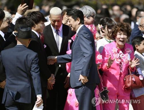 아베 신조 당시 총리가 작년 4월 도쿄 도심 공원인 '신주쿠 교엔'에서 열린 '사쿠라를 보는 모임' 행사에서 참석자들과 악수하고 있다. [교도=연합뉴스 자료사진]