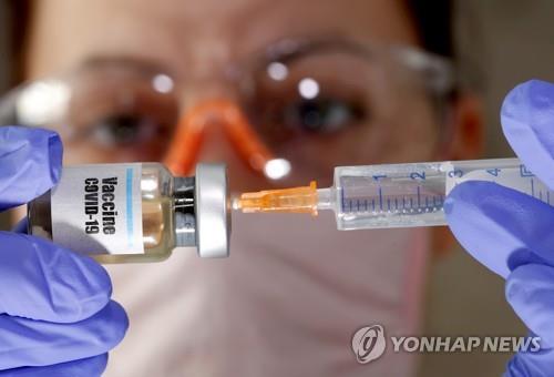 한 여성이 코로나19 백신이라고 쓰여진 병을 잡고 있다. [로이터=연합뉴스 자료사진]