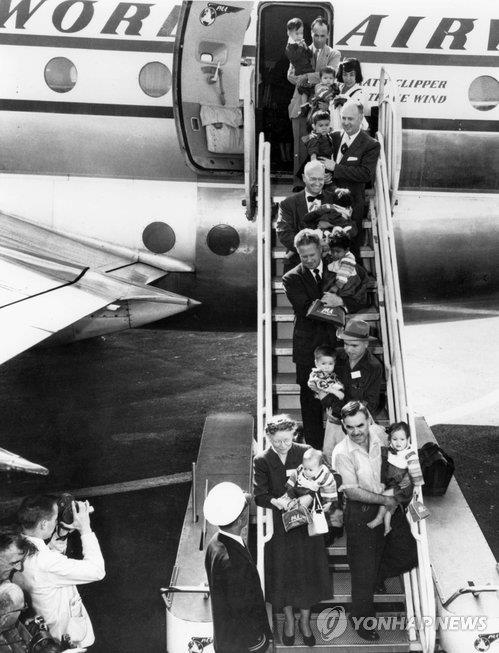 홀트 부부는 미국 난민구호법 시한이 종료되기 직전인 1956년 12월, 한국 입양아를 많이 실어나르려고 전세비행기를 동원했다. 미국 공항에 도착한 홀트 부부 일행이 아이들을 안고 비행기에서 내리고 있다. [국가기록원 제공]