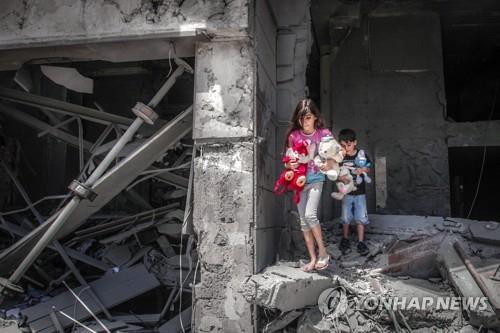 이스라엘군의 폭격으로 무너진 집에서 인형을 안고 나오는 가자지구 아이들