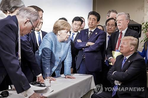 2018년 G7 정상회의 때 팔짱 낀 트럼프와 탁자 누른 메르켈 