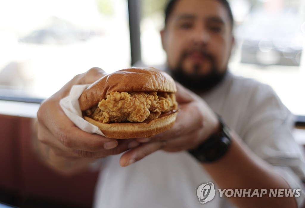 2019년 8월 22일 미국 텍사스주 카일 지역에서 한 남성이 파파이스가 최근 새로 출시한 치킨 샌드위치를 들어보이고 있다. [AP=연합뉴스자료사진]