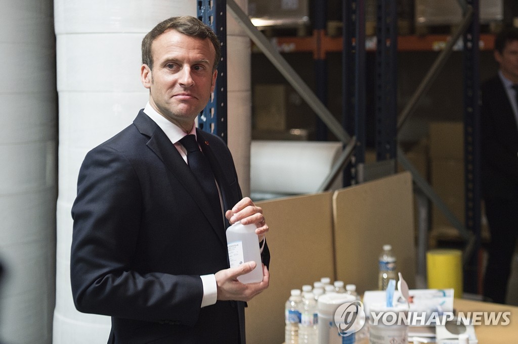 31일 의료용 마스크 공장을 방문한 에마뉘엘 마크롱 프랑스 대통령이 알코올 세정제를 들어보고 있다. [AP=연합뉴스] 