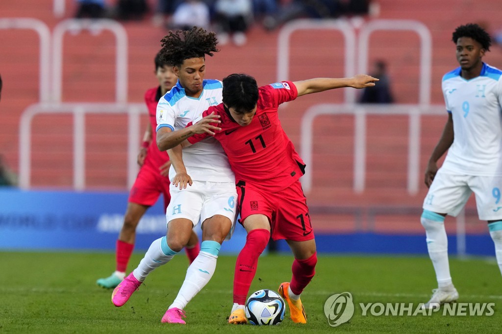In this Associated Press photo, Kang Seong-jin of South Korea (R) is held by David Ochoa of Honduras during a Group F match at the FIFA U-20 World Cup at Estadio Malvinas Argentinas in Mendoza, Argentina, on May 25, 2023. (Yonhap)