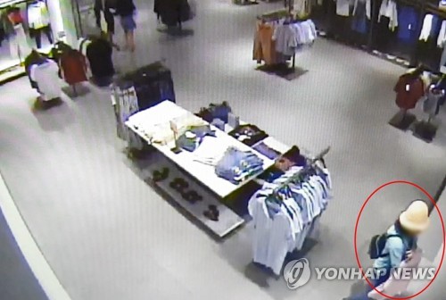의류매장 구석에서 쇼핑백에 옷을 넣고 있는 모습.