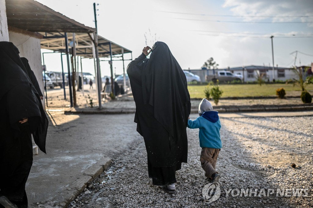 17일(현지시간) 시리아 북동부에 있는 수용소에서 IS에서 탈출한 프랑스 여성이 자녀와 함께 걷고 있다. [AFP=연합뉴스 자료사진]