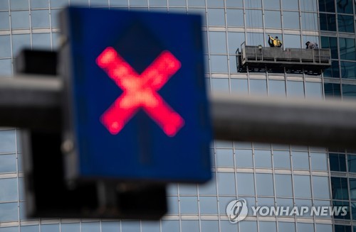 지난 16일 중국 베이징의 한 빌딩에서 근로자가 창문을 닦고 있는 가운데 신호등에 'X' 표시가 켜진 모습