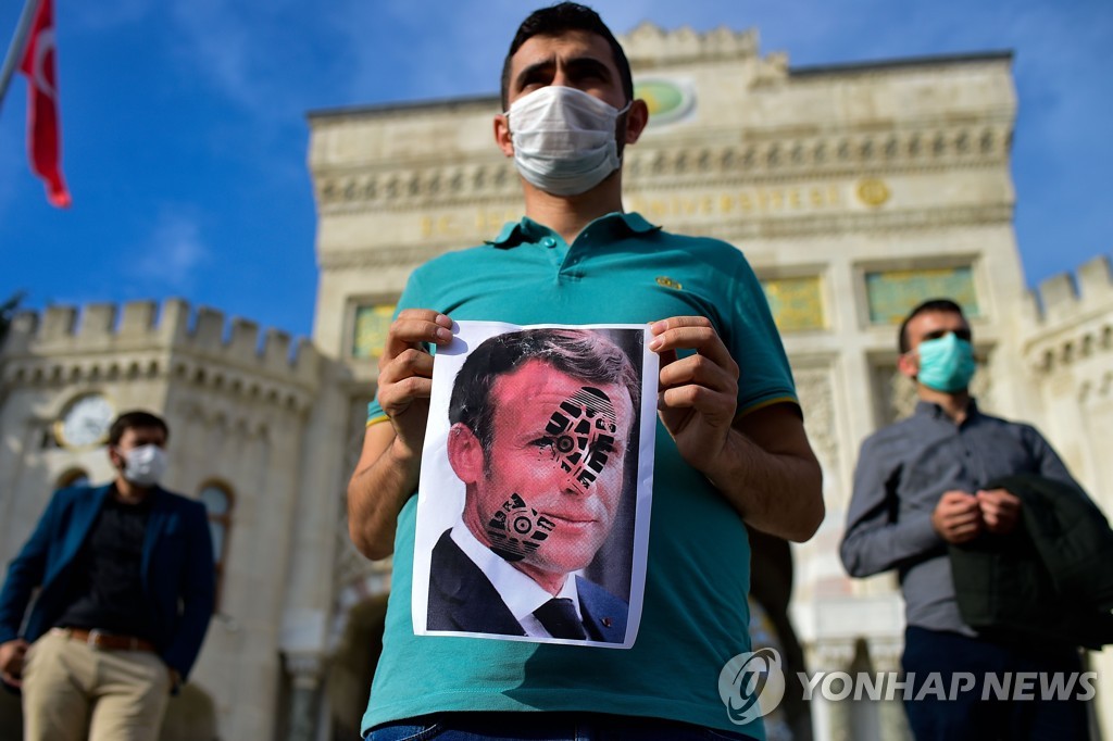 25일 터키 이스탄불에서 열린 반(反) 프랑스 집회에서 한 시민이 에마뉘엘 마크롱 프랑스 대통령의 얼굴에 구두 발자국이 찍힌 사진을 들고 있다. [AFP=연합뉴스]
