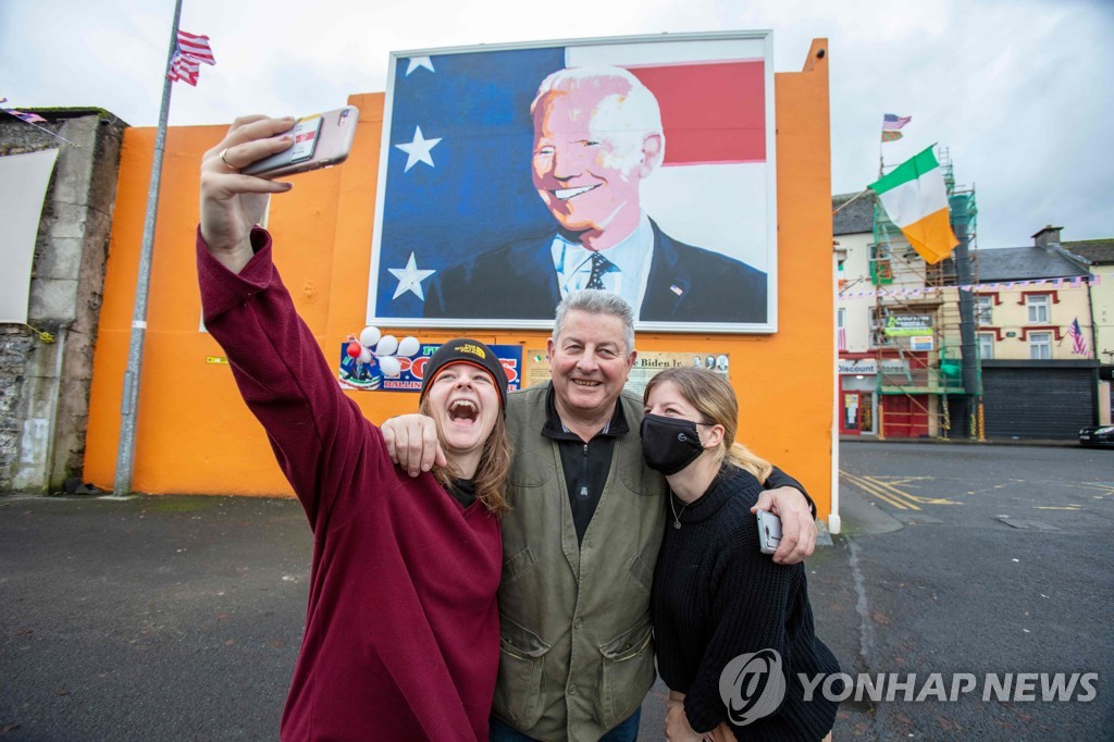 조 바이든 미 대통령 당선인의 벽화 앞에서 사진을 찍는 아일랜드 밸리나 마을 주민들 [AFP=연합뉴스]