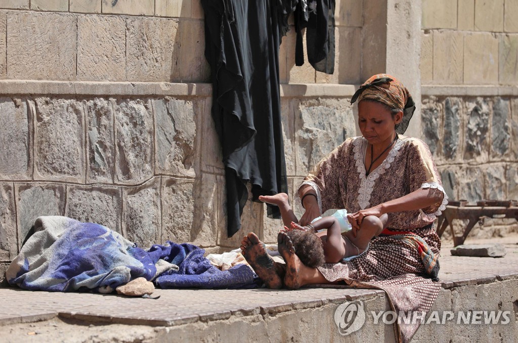 4일(현지시간) 내전으로 난민이 된 한 예멘 여성이 타이즈 주의 한 학교건물 앞에서 아기의 기저귀를 갈아주고 있다. [AFP=연합뉴스]