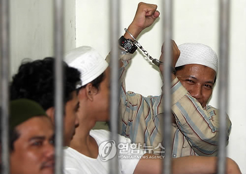 2010년 8월 26일 인도네시아 서부 아체주에 테러 훈련소를 세우려 한 혐의로 재판에 회부된 이슬람 성직자 아만 압두라흐만이 웃으며 수갑을 찬 손을 들어보이고 있다. [EPA=연합뉴스]