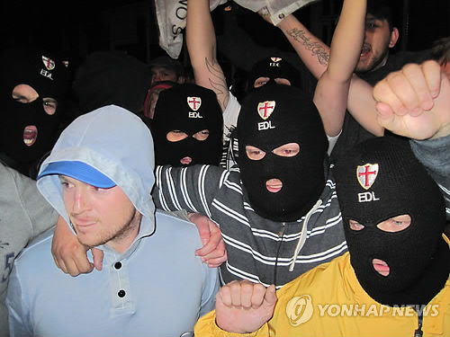 지난 22일(현지시간) 낮 영국 런던 동남부 울위치의 왕립 포병대기지 인근 대로에서, 테러 용의자 2명이 흉기를 휘둘러 군인으로 추정되는 20대 남자가 목숨을 잃고 2명이 부상했다. 사진은 사건후 울리치 시내에서 극우단체 영국수호동맹(EDL) 지도자인 토미 보빈슨(왼쪽)이 복면을 한 지지자들과 시위를 하는 모습.(AP=연합뉴스DB) * 영국내 사용금지; 판매·보관 불가