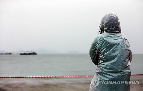 <세월호참사> 야속한 날씨세월호 침몰 12일째인 27일 오전 전남 진도군 팽목항에서 우비를 입은 한 실종자 가족이 바다를 바라보고 있다. 2014.4.27