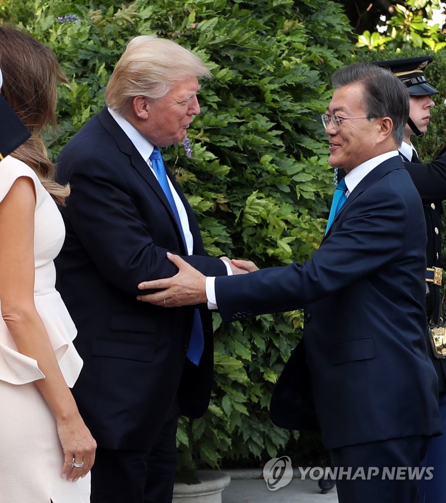 ホワイトハウスの玄関で握手を交わす文大統領（右）とトランプ大統領＝２９日、ワシントン（聯合ニュース）