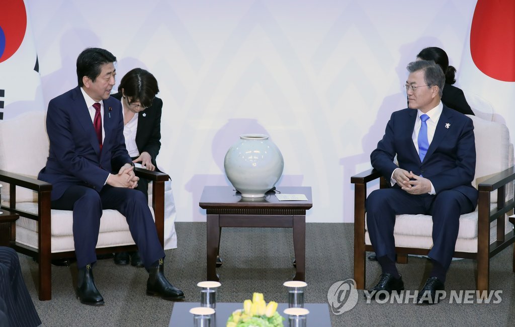 文大統領（右）は９日、平昌冬季五輪の開会式に出席するため来韓した安倍首相と会談した＝（聯合ニュース）