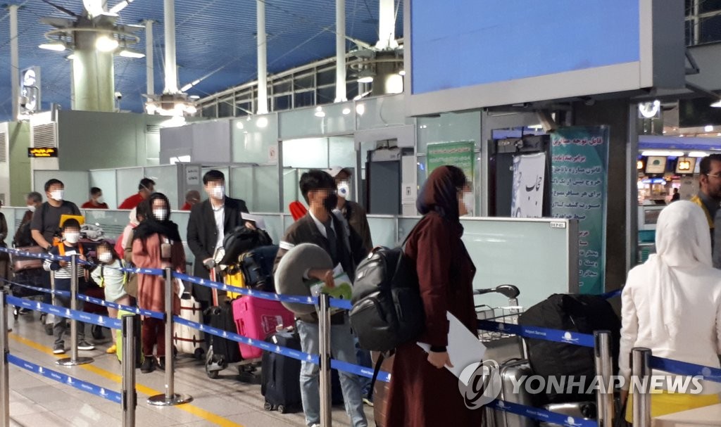 South Koreans and their Iranian family members stand in line to go through immigration processes at Imam Khomeini International Airport in Tehran on March 19, 2020, as they were set to return home on chartered flights via Dubai, following a spike in coronavirus infections in the Middle Eastern country. (Yonhap)