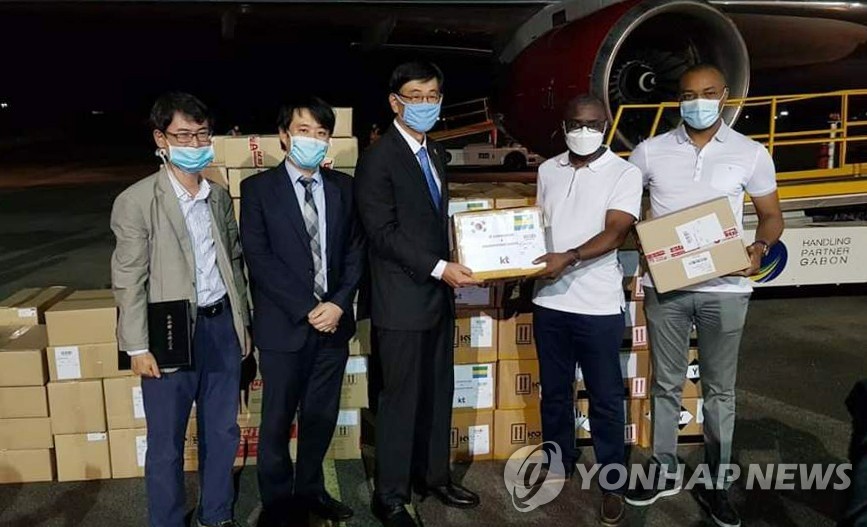 This photo, provided by the South Korean Embassy in Gabon, shows Gabonese government officials (1st and 2nd from R) posing for a photo upon the arrival of 50,000 coronavirus test kits from South Korea at Libreville International Airport in the Gabonese capital city of Libreville on April 18, 2020. (PHOTO NOT FOR SALE) (Yonhap)