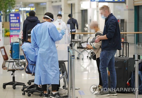 International arrivals show their passports to officials who wore protective gear at Incheon International Airport, South Korea's main gateway west of Seoul, on Oct. 22, 2020. (Yonhap)