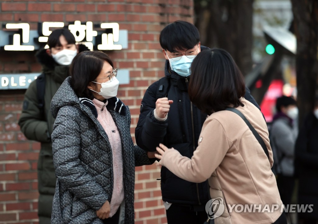 A student taking the College Scholastic Ability Test raises his fist in a show of determination before entering a test center at a high school in Seoul on Dec. 3, 2020. (Yonhap)