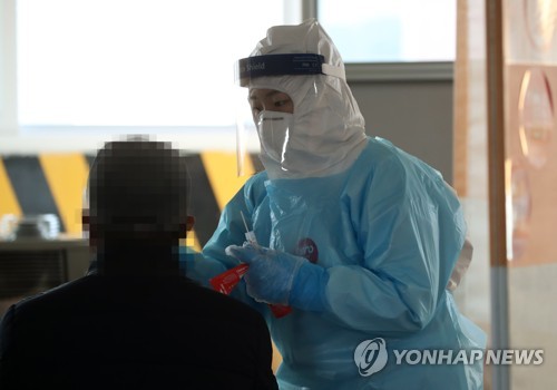 This photo taken on Jan. 20, 2021, shows a health worker clad in protective suit collecting a sample from a citizen at a makeshift virus testing clinic in the southwestern city of Gwangju. (Yonhap)