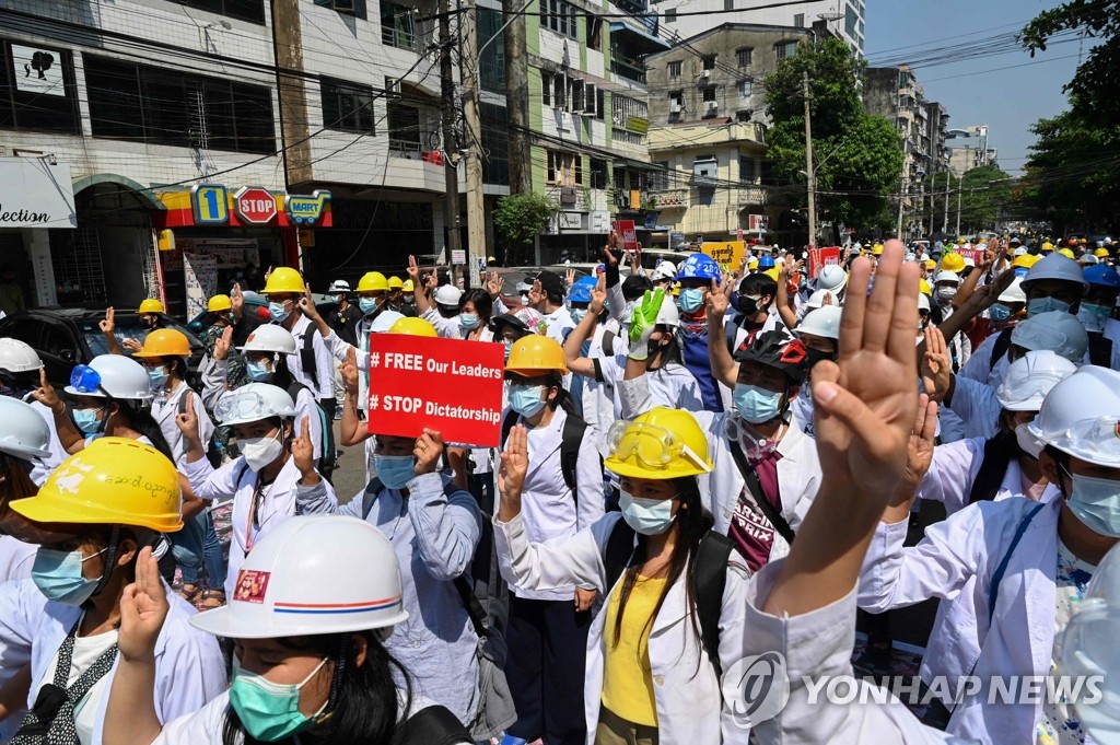 미얀마 양곤에서 지난 5일 의료인과 학생들이 쿠데타에 항의하는 시위를 벌이며 저항의 표시로 세 손가락을 세우고 있다. [AFP=연합뉴스 자료사진]