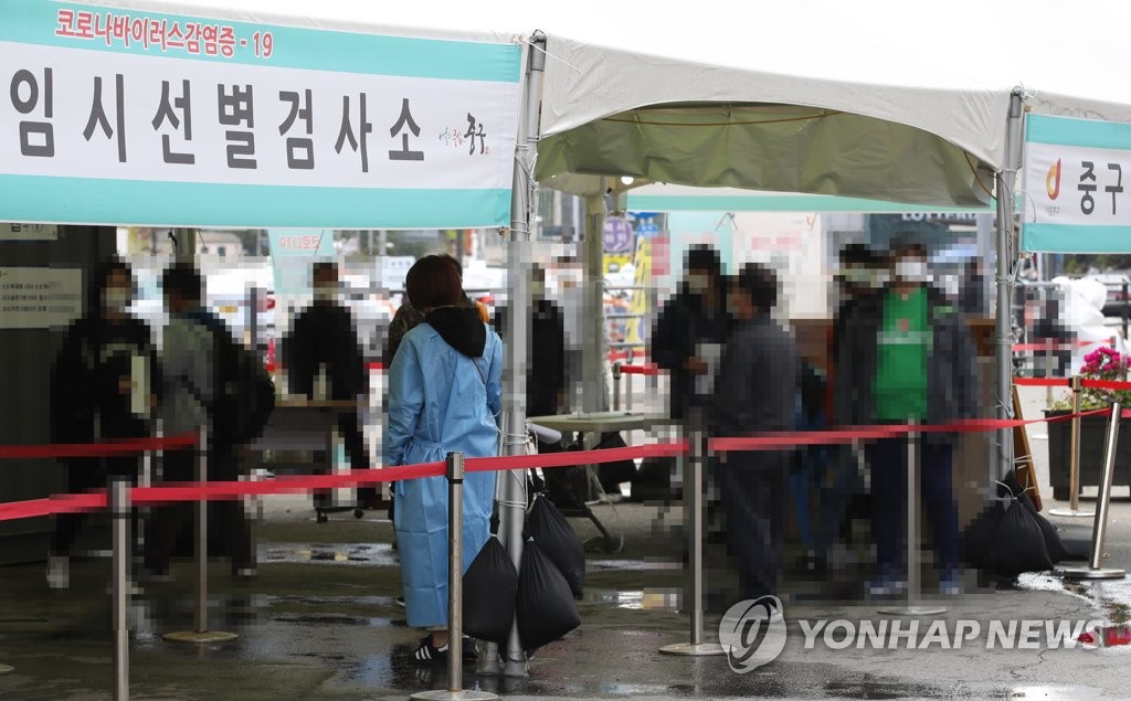 People stand in line for COVID-19 testing at a temporary screening station in front of Seoul Station on April 18, 2021. (Yonhap)