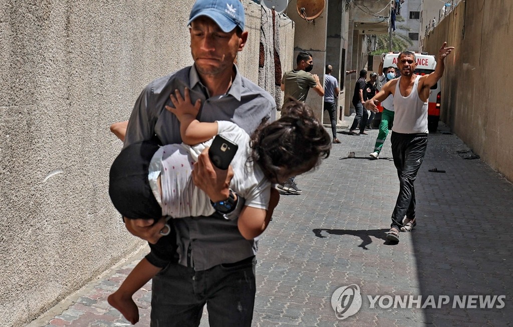 이스라엘군 공습에 아이 안고 대피하는 팔레스타인 남성