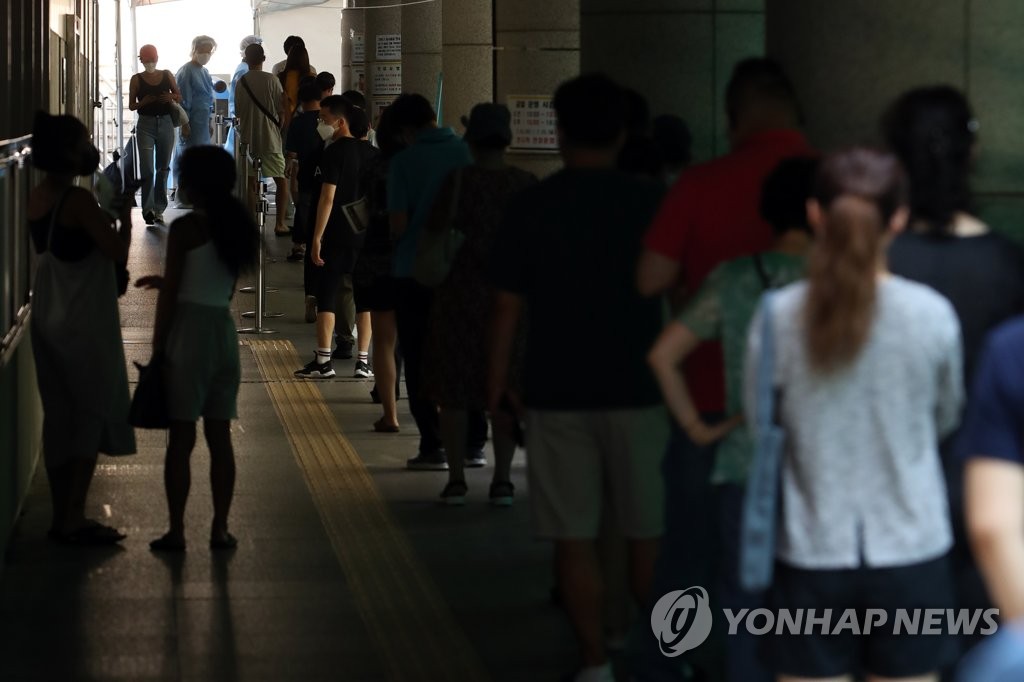 This photo, taken on July 22, 2021, shows citizens waiting in line to get COVID-19 tests at a makeshift testing site in central Seoul. (Yonhap)