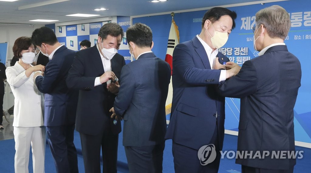 서로에게 배지 달아주는 민주당 대선 예비후보들