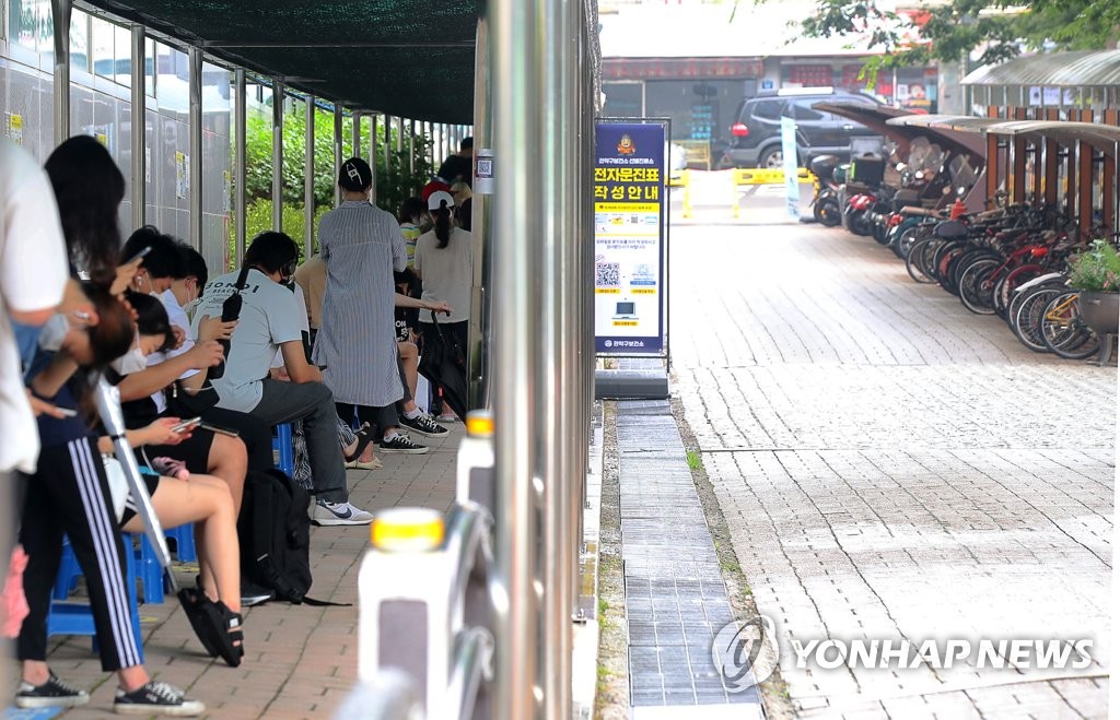 This photo taken on Aug. 1, 2021, shows people waiting to receive a coronavirus test at a makehisft testing facility in southern Seoul amid heat wave. (Yonhap) 