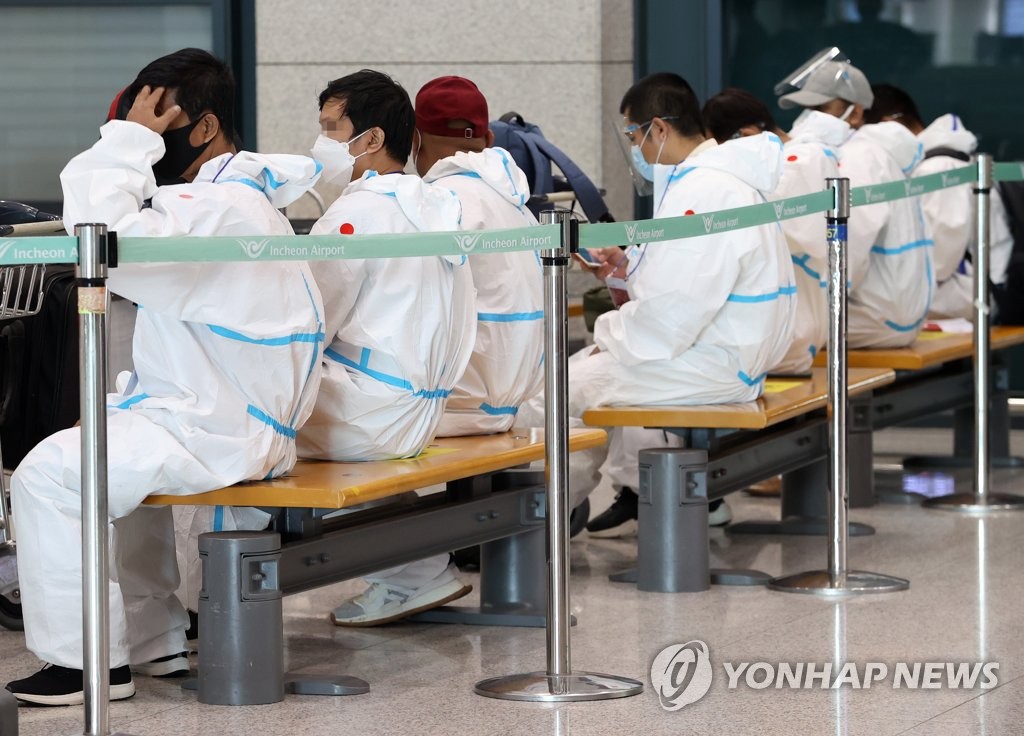 仁川国際空港に到着した外国人。防護服を着用している＝２日、仁川（聯合ニュース）