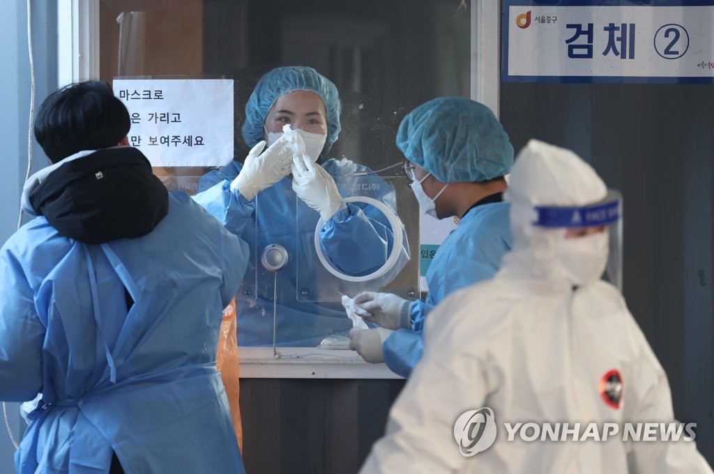 Une employée du centre de dépistage du nouveau coronavirus (Covid-19) installé à la gare de Séoul enlève de la glace qui s'est formée sur une vitre, le matin du jeudi 6 janvier 2022. Les autorités ont rapporté le même jour 4.126 nouveaux cas d'infection au Covid-19 et 882 patients gravement malades.