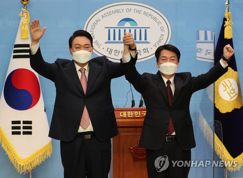 Yoon Suk-yeol (L), the presidential candidate of the main opposition People Power Party, and Ahn Cheol-soo, the presidential candidate of the minor opposition People's Party, pose for photos at the National Assembly in Seoul on Feb. 3, 2022, after holding a joint press conference to announce that Ahn will drop out of the March 9 election and back Yoon as a unified candidate. (Pool photo) (Yonhap)
